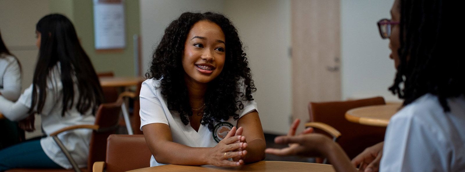 A USF student speaking with an advisor during a campus advising conversation in a bright, welcoming academic setting. The student appears engaged and focused while the advisor listens, creating a supportive and encouraging educational atmosphere.