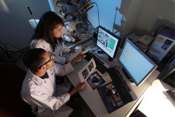 Two people in white lab coats looking at a computer screen
