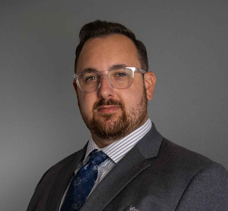 Tyler Benning wearing a dark grey suit with a blue tie