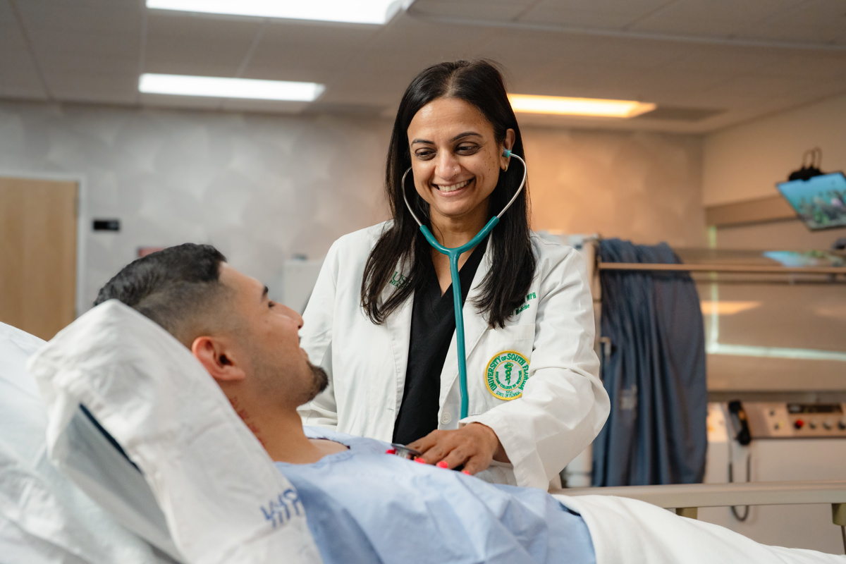 Medical professional in a white coat checking a patients heart beat in exam room