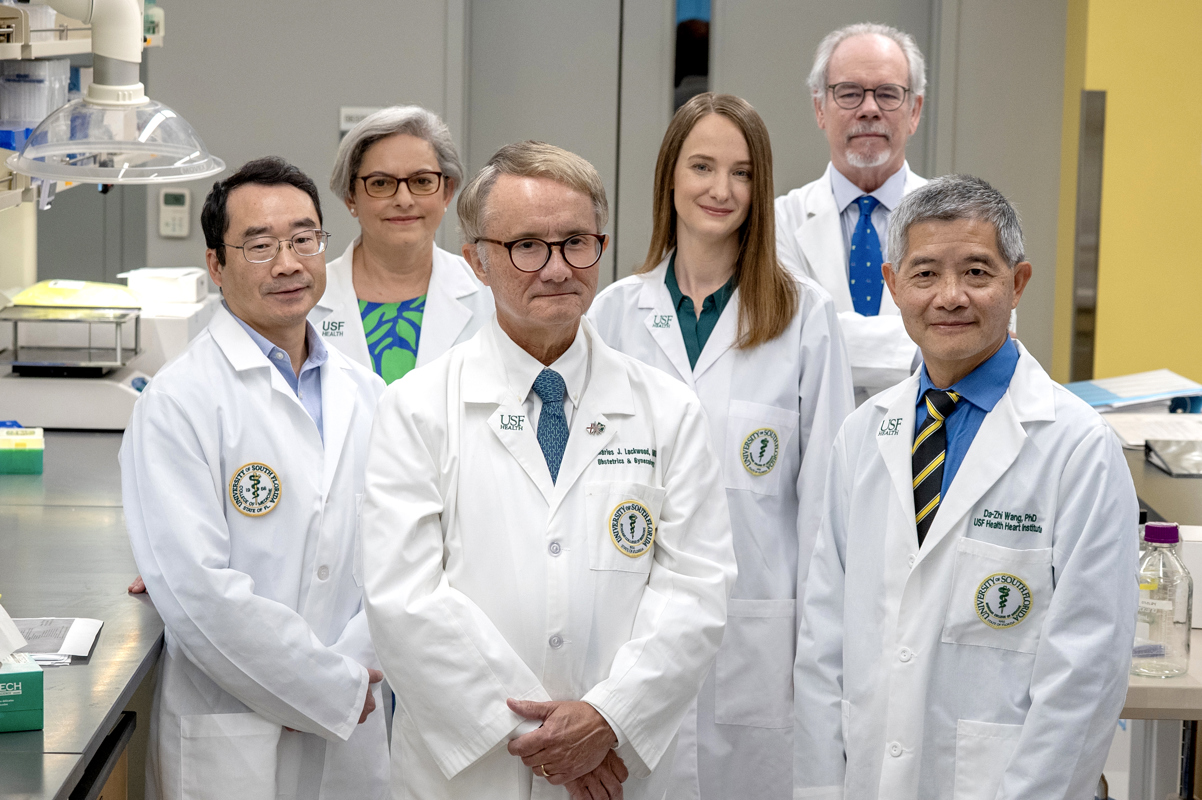 A group of medial professionals wearing medial white coats stand together in a lab