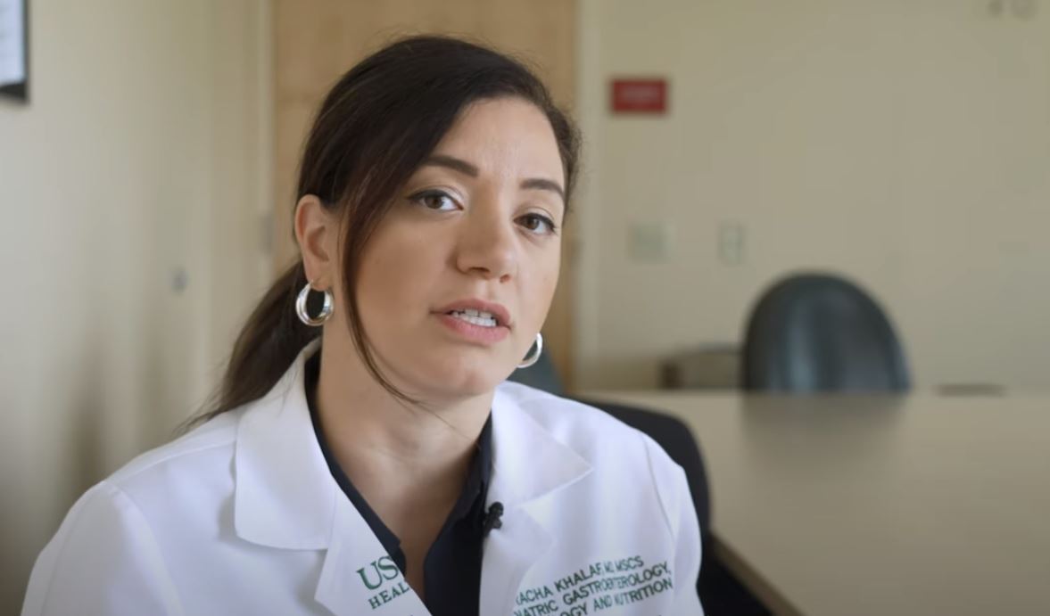 Dr. Khalaf sitting at a table in her medical white coat