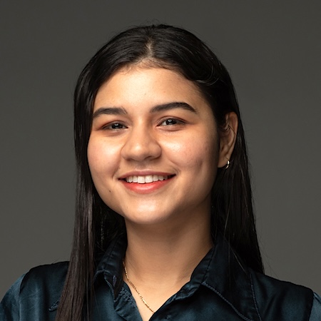 A woman with dark hair smiles in a dark green blouse
