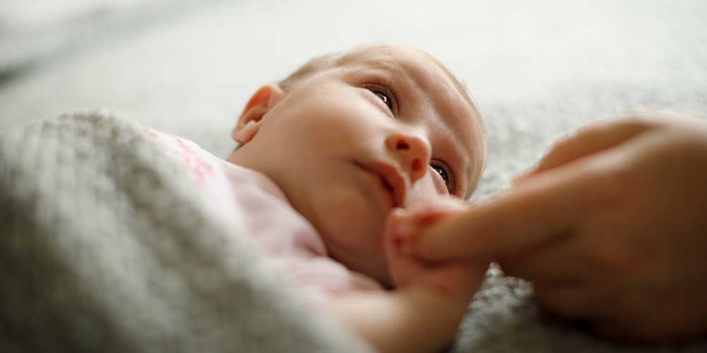 Newborn baby holding mother's hand