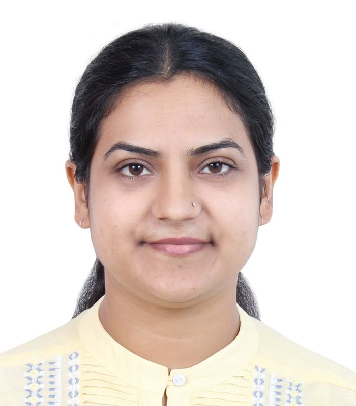 Dr. Alka Rani, PhD smiles wearing a yellow blouse with blue and white embroidery 