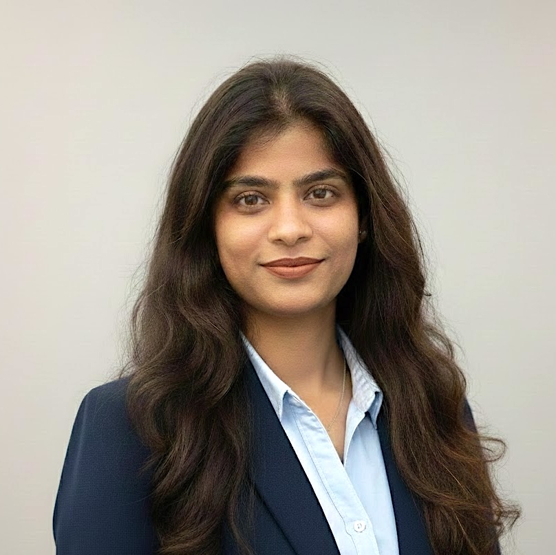A woman with long brown hair smiles in a suit coat